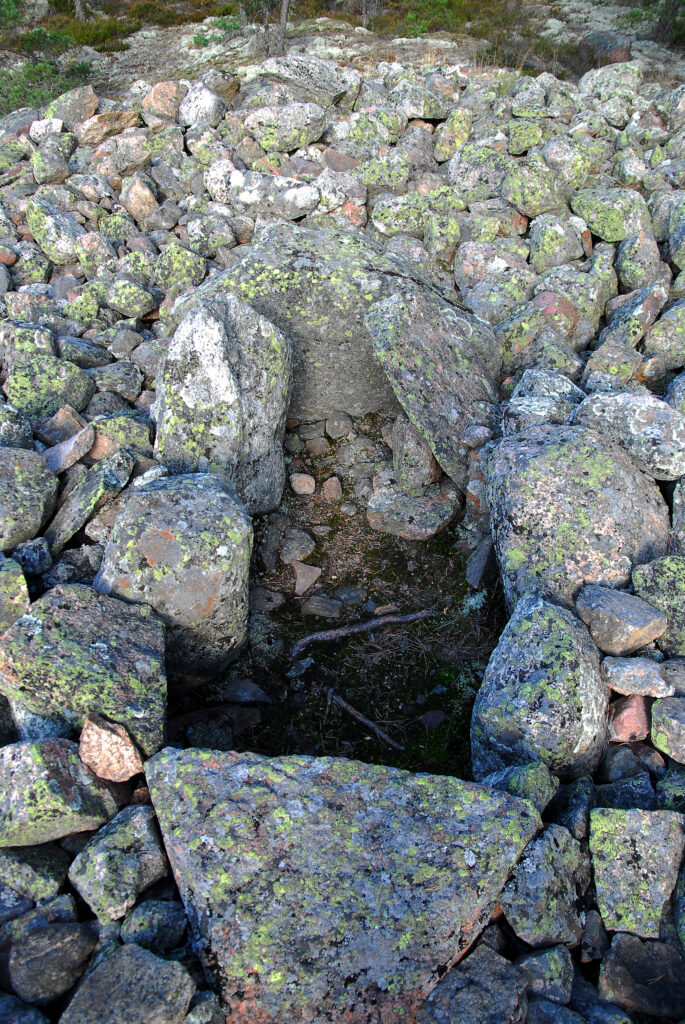 Kuvassa näkyy isoista kivistä muodostetuu arkkumainen rakenne, jossa on sivuissa isompia kiviä ja päädyissä yksi isompi kivi.