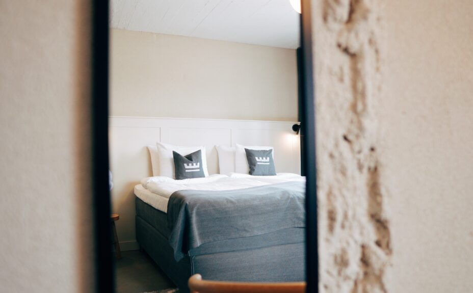 Loft Hotel Rauman huone ja sänky. Sängyllä on tyynyjä hotellin logolla.