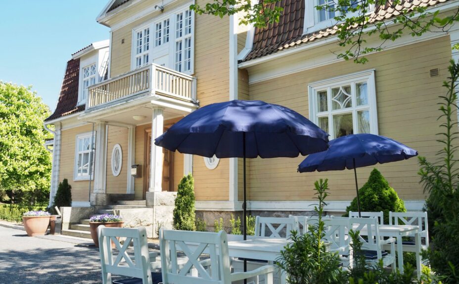 Johtola building in summer. Tables, chairs and umbrellas in front of the building.