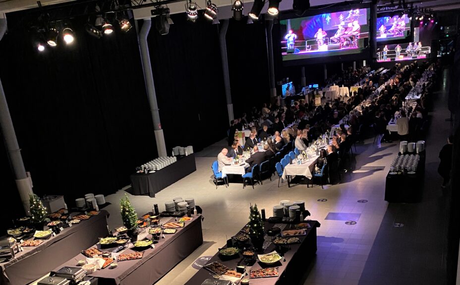 Kivikylä Arena. Long tables with food and people enjoying the live show.