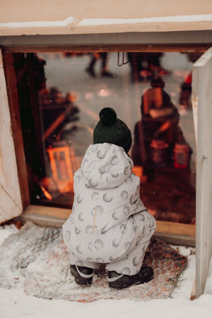 A child peeking into a basement in the Christmas Elf Courtyard in Tammela.