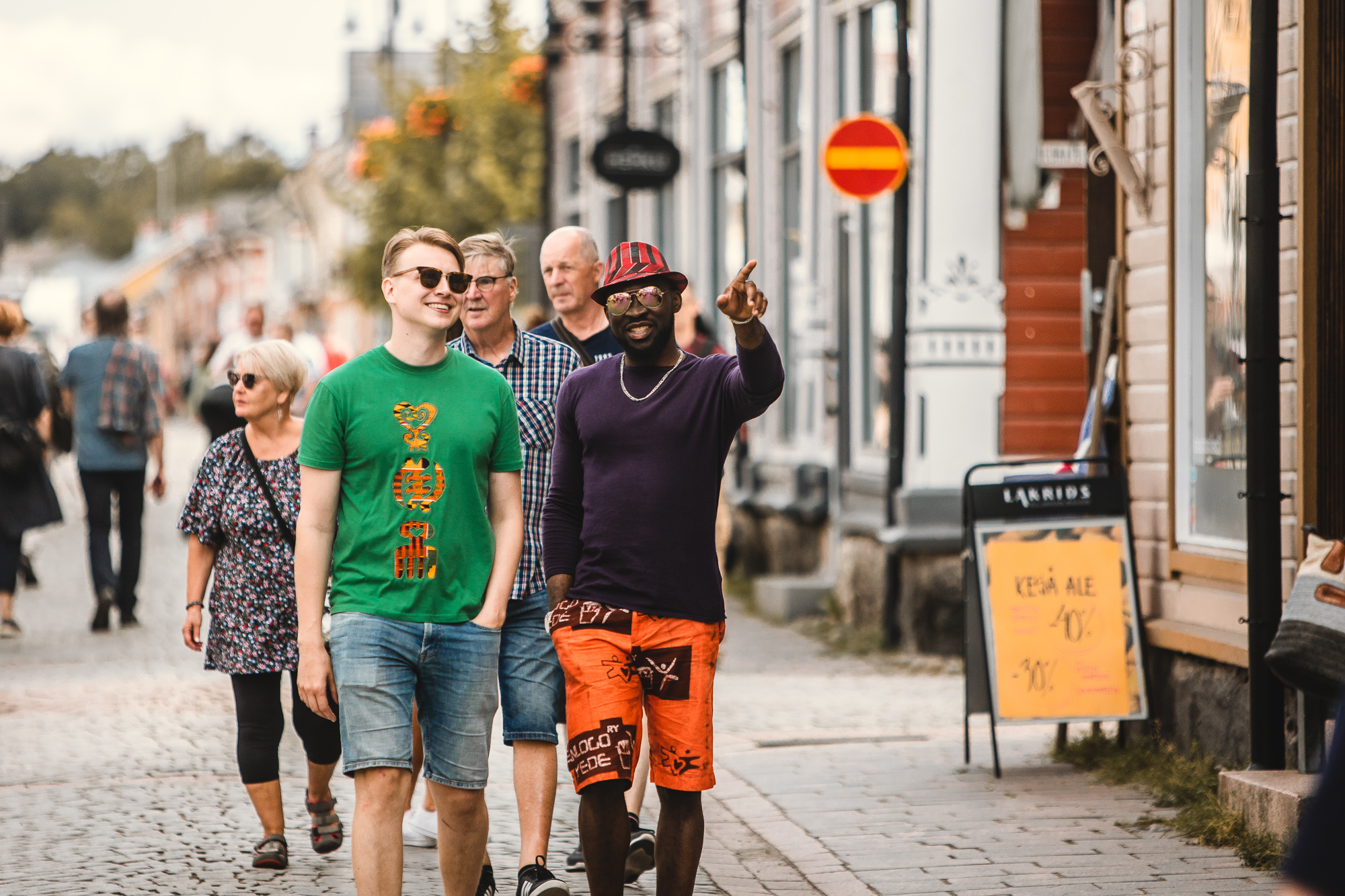 Miehet kävelemässä Vanhassa Raumassa. Yksi osoittaa jonnekin sormellaan.