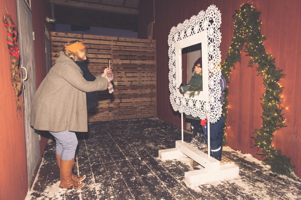 A woman takes a picture of a child by the Christmas in Lace Town frames.