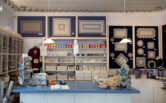 Pits-Priia, a bobbin lace store. Lace items on the wall and products on the shelves.