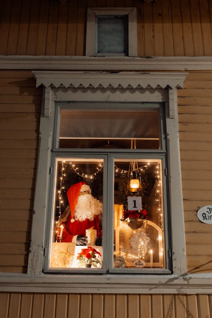 Window decorated with Santa Claus, presents and Christmas lights.