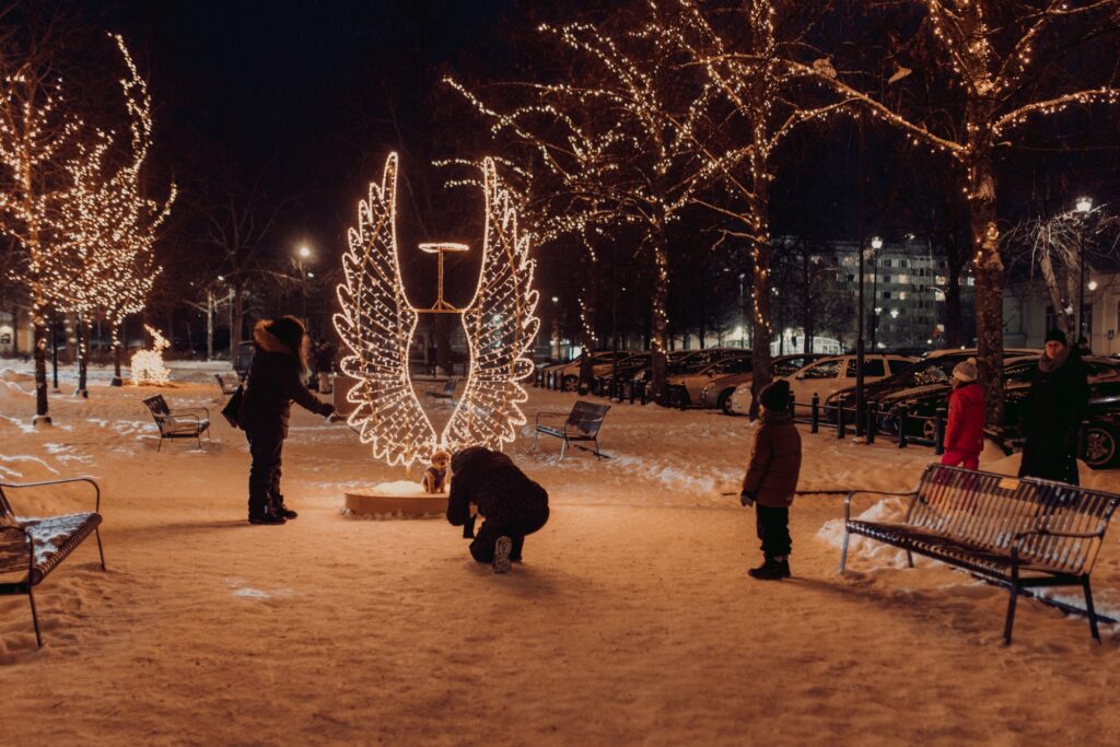 People taking pictures with illuminated angel wings in Savilanpuisto park.